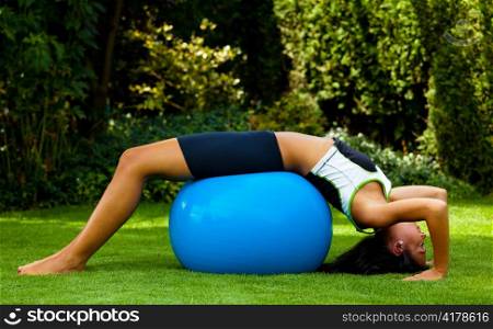 a young woman of power exercises on an exercise ball