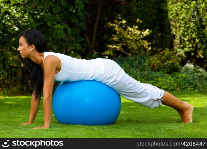 a young woman of power exercises on an exercise ball