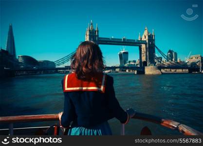 A young woman on a boat is looking at Tower bridge and the London skyline