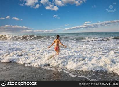 A young woman playing in the waves on a sea beach