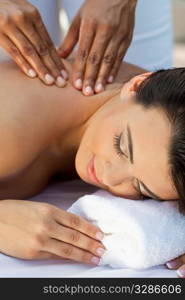 A young woman relaxing at a health spa while having a massage