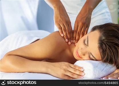 A young woman relaxing outside at a health spa while having a massage. Woman At Health Spa Having Relaxing Outdoor Massage