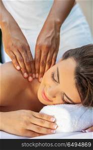 A young woman relaxing outside at a health spa while having a massage. Woman At Health Spa Having Relaxing Massage