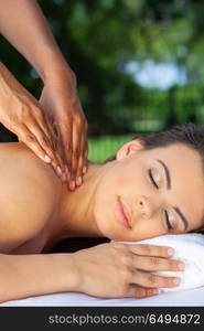 A young woman relaxing outside at a health spa while having a massage. Woman At Health Spa Having Relaxing Massage