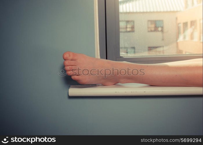 A young woman&rsquo;s foot resting on a window sill