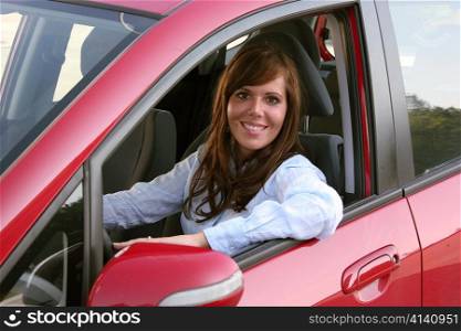 a young woman sits in her first car and is looking forward
