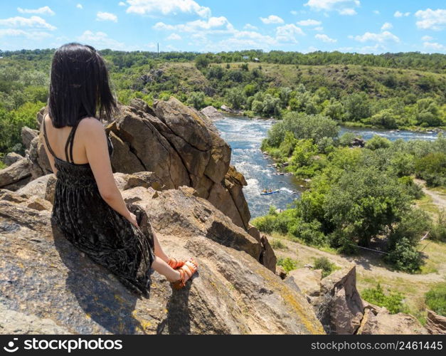 A young woman sits on a rock and looks at a picturesque landscape of the southern bug river. Bug Guard national nature park in Ukraine. Stock photography.. A young woman sits on a rock and looks at a picturesque landscape of the southern bug river. Bug Guard national nature park in Ukraine. Stock photo.
