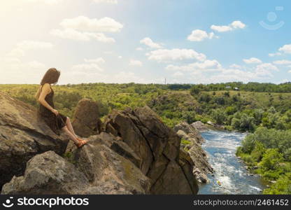 A young woman sits on a rock and looks at a picturesque landscape of the southern bug river. Bug Guard national nature park in Ukraine. Stock photography.. A young woman sits on a rock and looks at a picturesque landscape of the southern bug river. Bug Guard national nature park in Ukraine. Stock photo.