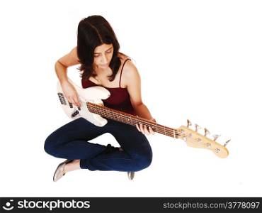 A young woman sitting on the floor, playing her guitar, isolated on whitebackground.