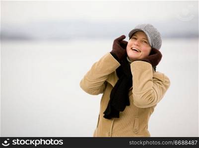 A young woman smiling by the ocean in winter.
