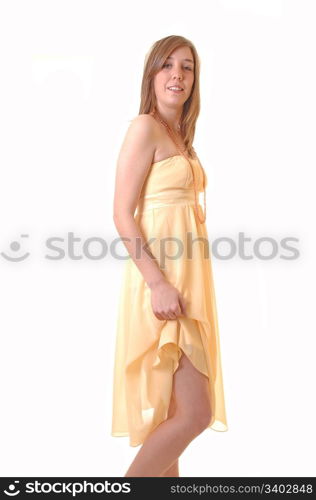 A young woman standing in a yellow long dress and lifting one site upto show her legs, for white background.