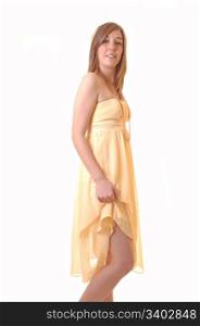 A young woman standing in a yellow long dress and lifting one site upto show her legs, for white background.