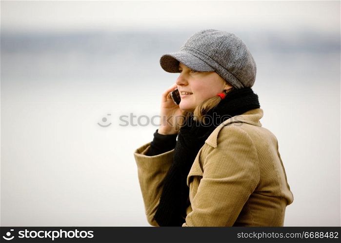 A young woman talking on a cell phone in winter.