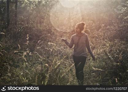 A young woman walking trekking through a green path in forest mountain summer sunrise thailand.