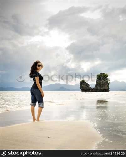 A young woman walks alone on a beach