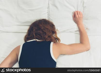 A young woman wearing a dress is passed out on a bed