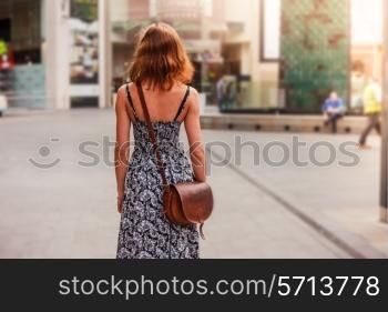 A young woman wearing a dress is walking in the street