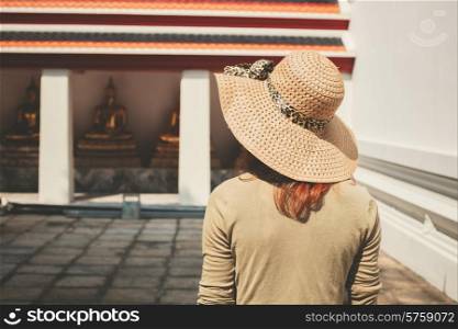 A young woman wearing a hat is exploring a buddhist temple