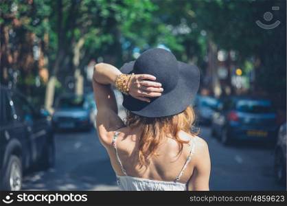A young woman wearing a hat is walking in the street