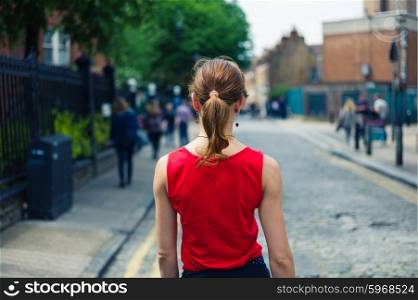 A young woman wearing a skirt is walking on a cobbled street in the summer