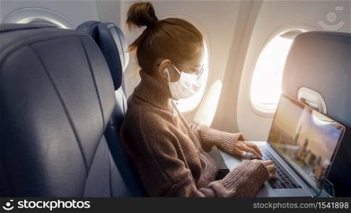 A young woman wearing face mask is traveling on airplane , New normal travel after covid-19 pandemic concept