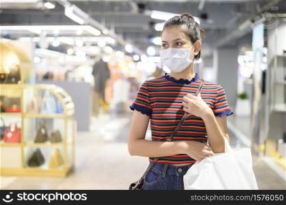A young woman wearing facial mask shopping in mall.