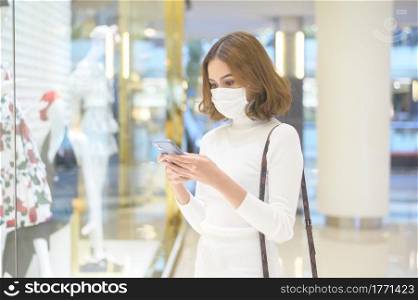 A young woman wearing protective mask in shopping mall, shopping under Covid-19 pandemic concept.. Young woman wearing protective mask in shopping mall, shopping under Covid-19 pandemic concept.