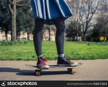 A young woman wearing trendy clothes is skateboarding in a park