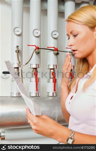 a young woman with a billing of heating costs for heating. in the boiler room.