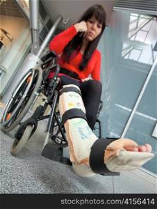a young woman with a broken leg. leg in plaster and wheelchair