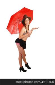 A young woman with a red umbrella, black mini skirt, boots and brastanding for white background in the studio.
