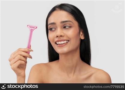 A young woman with clear,spotless skin looking at a hair removal razor.