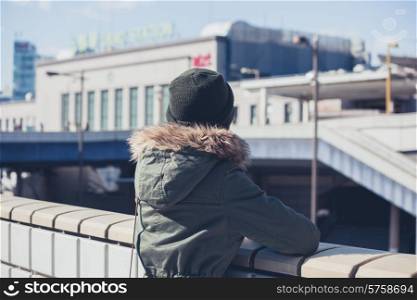 A ywoman is looking at a train station in the city in winter