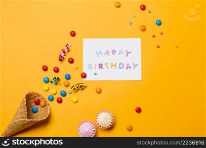 aalaw gems streamers from cone near happy birthday message yellow background
