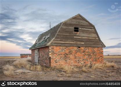 abandoned brick barn and farm buildings in eastern Colorado prairie at dusk