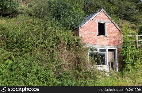 Abandoned brick house set into hillside in England with door falling in