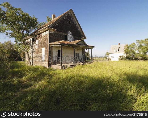 Abandoned farm house in rural field.