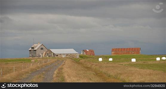 Abandoned farmsted with house, barns, and hay bales