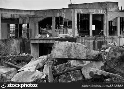 Abandoned marble processing factory and pile of granite slates. Black and white.