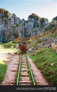 Abandoned mine train track with cart and bridge on a sunny day. Abandoned mine train track