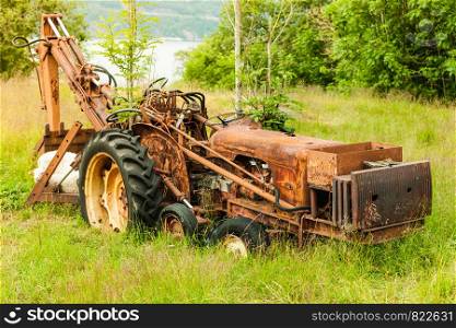 Abandoned old agricultural machinery covered with rust in high grass. Outdoor shot on sunny day.. Old agricultural machinery covered with rust