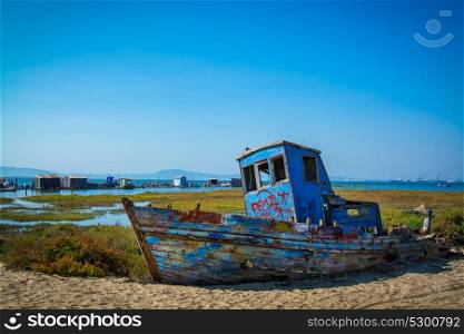 abandoned old fishing boat lying on sand in comporta, alentejo Portugal.