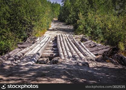 Abandoned old wooden bridge to the dirt road among the deciduous trees and shrubs.. Abandoned Old Wooden Bridge