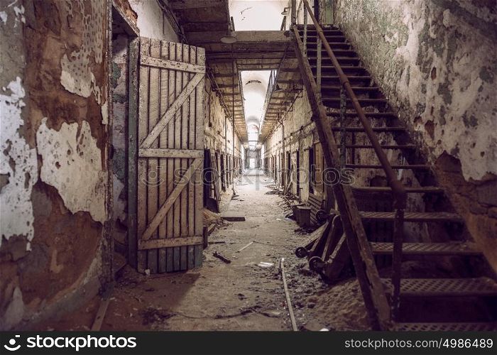 Abandoned prison cell walkway with old rusty stairs, doors and peeling walls. Philadelphia Eastern State Penitentiary.