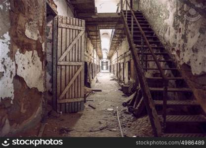 Abandoned prison cell walkway with old rusty stairs, doors and peeling walls. Philadelphia Eastern State Penitentiary.
