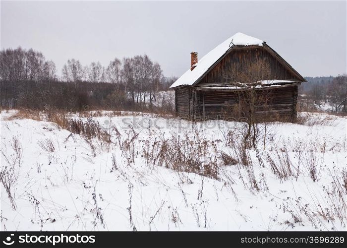 abandoned rural house in snow-covered village in winter day