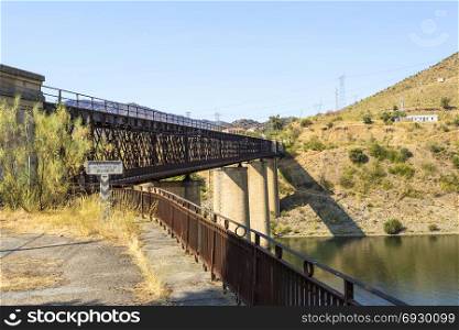 Abandoned truss road-rail bridge with the rail track above the roadway crossing the Douro River in Pocinho, Douro region, Portugal