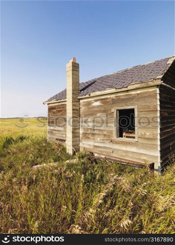Abandoned wooden house in state of disrepair in rural countryside.