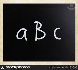 ""abc" handwritten with white chalk on a blackboard"