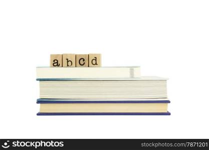 abcd word on wood stamps stack on books, alphabet and english language concepts